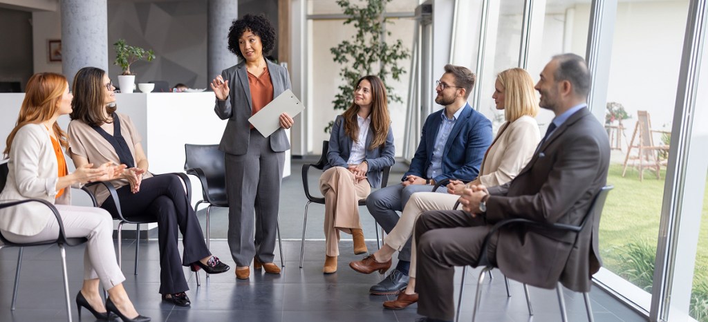group of professionals sitting in circle with woman leading conversation