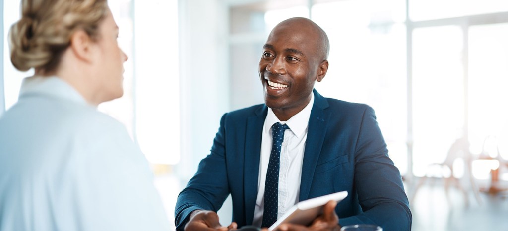 man in suit smiling and talking to woman